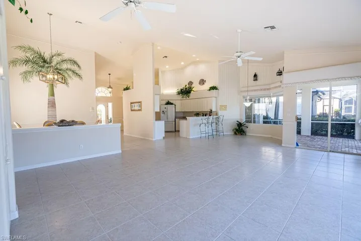 Living room with high vaulted ceiling, light tile patterned flooring, and a ceiling fan