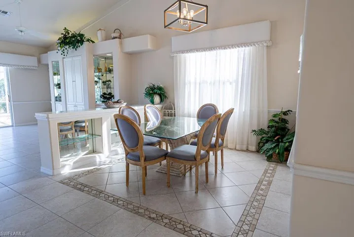 Dining area with inlaid floor details, light tile patterned floors, and high vaulted ceiling