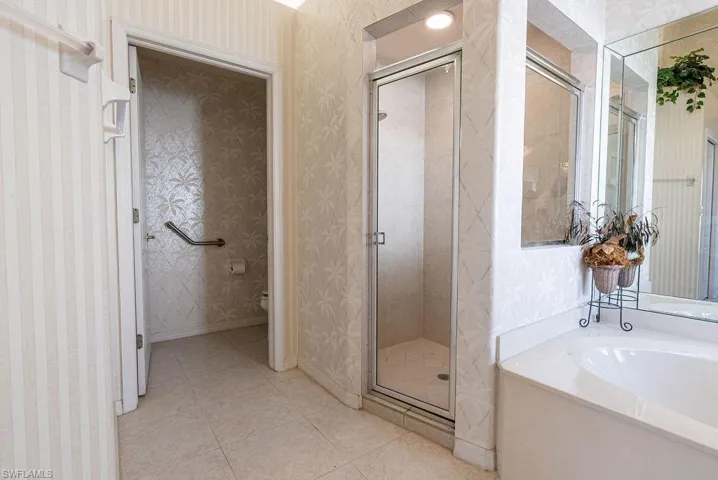 Full bathroom featuring wallpapered walls, a shower stall, a bath, and light tile patterned floors