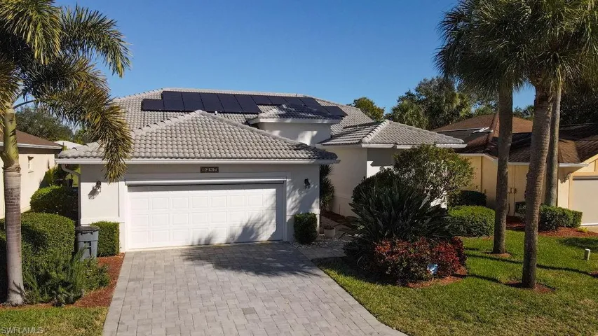View of front of home with a tile roof, decorative driveway, stucco siding, solar panels, and a garage