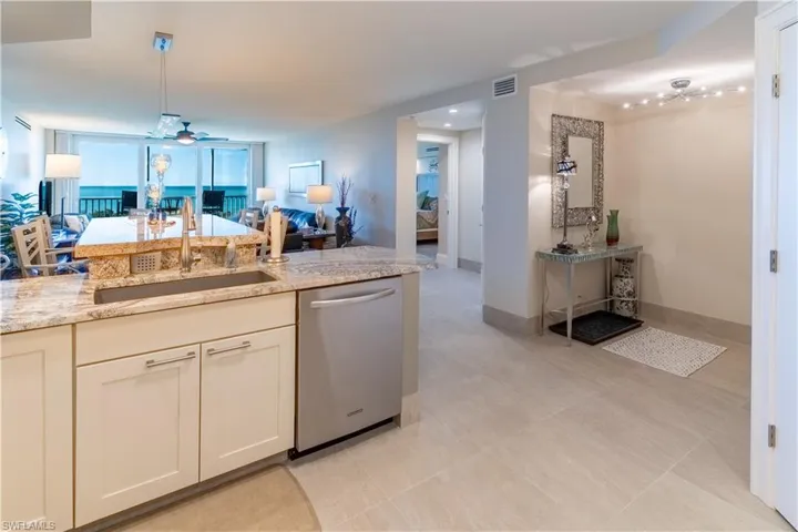 Kitchen featuring open floor plan, a ceiling fan, dishwasher, light stone countertops, and decorative light fixtures