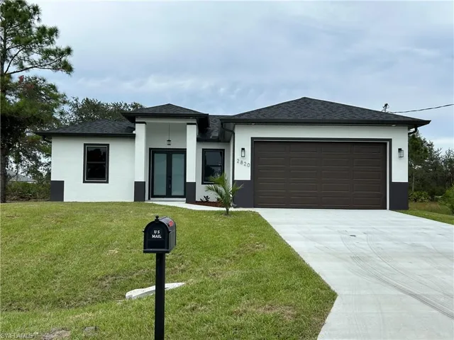 View of front facade featuring a front lawn and a garage