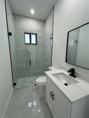 Bathroom with a shower with shower door, toilet, and vanity