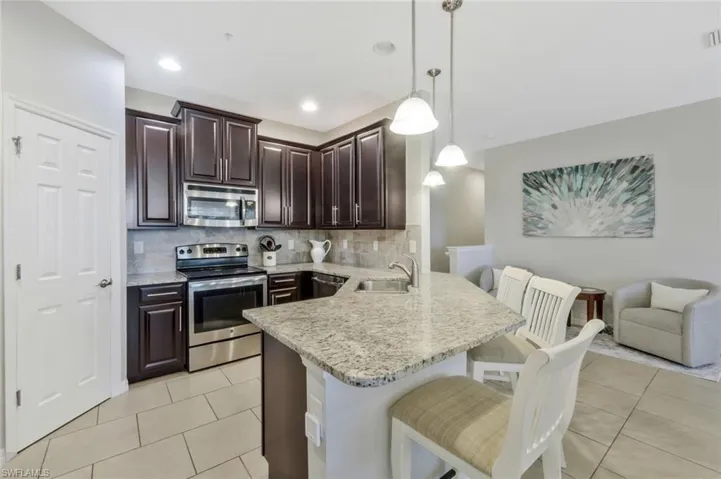 Kitchen featuring sink, a breakfast bar area, hanging light fixtures, kitchen peninsula, and stainless steel appliances