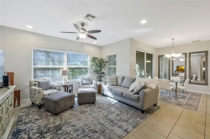 Tiled living room with ceiling fan with notable chandelier