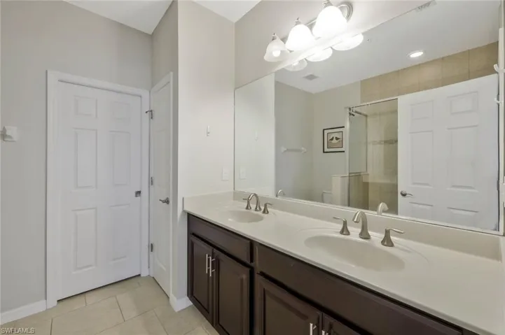 Bathroom featuring vanity, a shower with door, tile patterned floors, and toilet