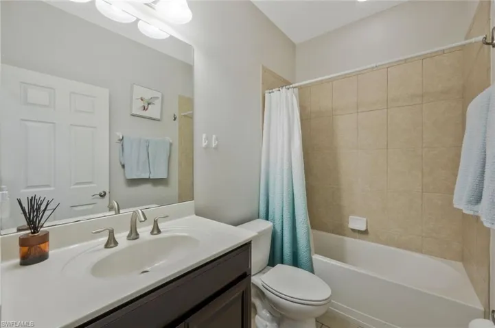 Full bathroom featuring vanity, shower / bath combination with curtain, and toilet
