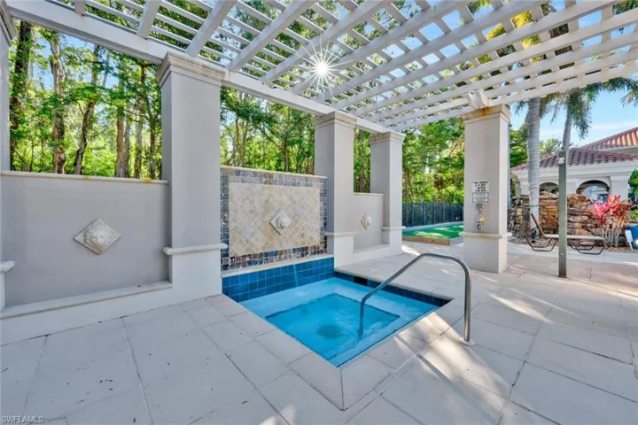 View of hot tub featuring an in ground hot tub/spa under a pergola.