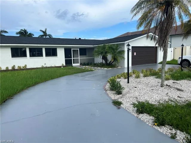 Single story home with stucco siding, driveway, a garage, a sunroom, and a front yard