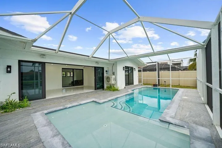 View of pool featuring a sun shelf, a patio, and glass enclosure