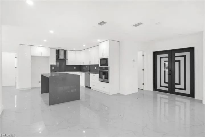 Kitchen featuring white cabinets, modern cabinets, light marble finish floors, stainless steel appliances, and a center island