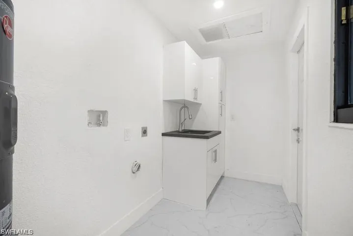 Laundry room featuring light marble finish flooring, hookup for an electric dryer, cabinet space, water heater, and washer hookup