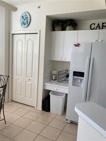 Kitchen featuring white fridge with ice dispenser, light countertops, white cabinetry, and light tile patterned flooring