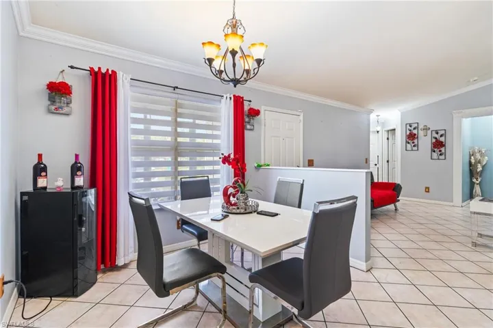 Dining area with crown molding, suspended lighting, and light tile patterned floors