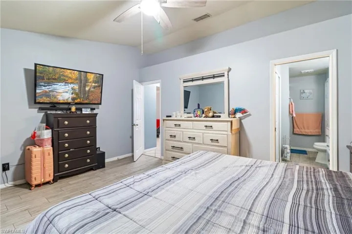 Bedroom with wood finish floors, a ceiling fan, and ensuite bathroom