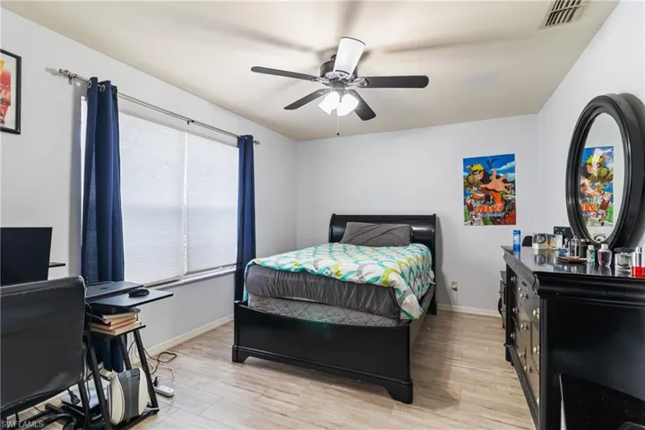 Bedroom featuring light wood-type flooring, a ceiling fan, and a desk