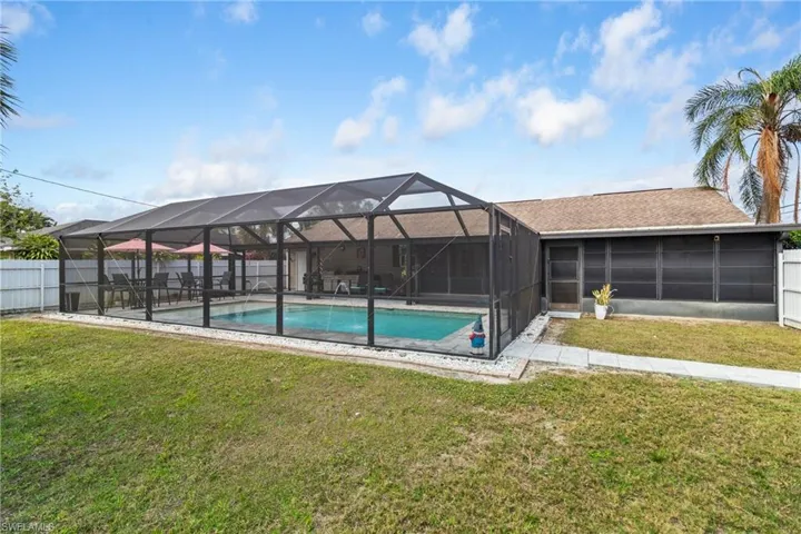 View of pool with a fenced backyard, a sunroom, and glass enclosure