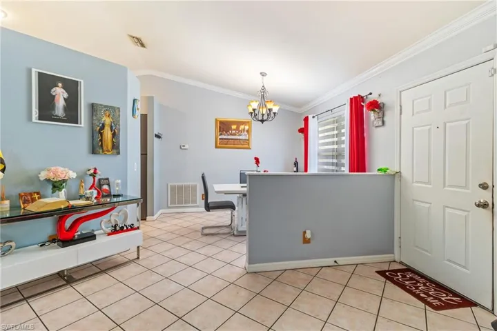 Dining space featuring ornamental molding, hanging lights, and light tile patterned floors