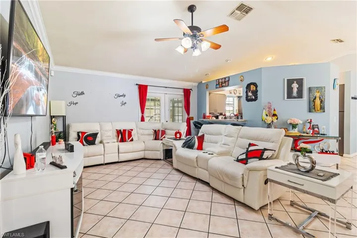Living area featuring crown molding, a ceiling fan, and light tile patterned floors