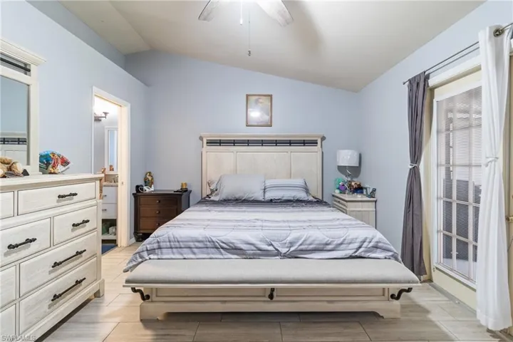 Bedroom featuring lofted ceiling, a ceiling fan, and connected bathroom
