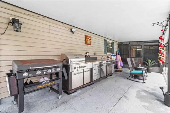 View of patio with exterior kitchen and a sunroom