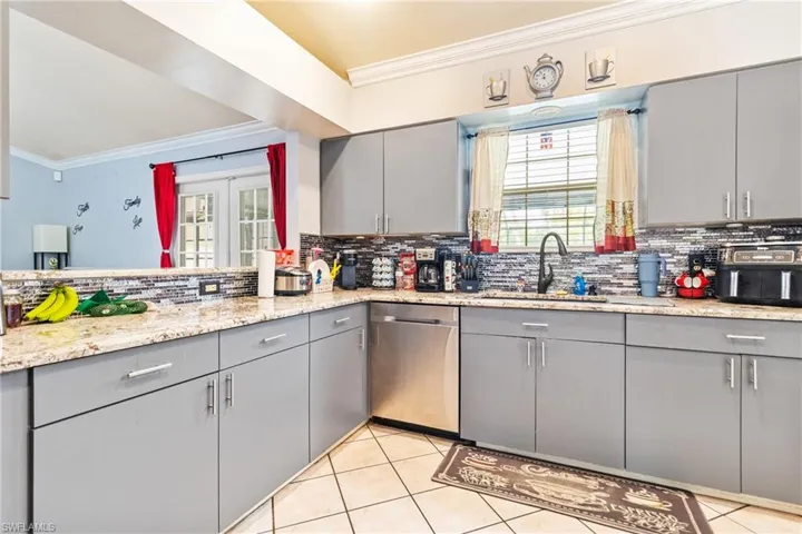 Kitchen featuring gray cabinets, ornamental molding, dishwasher, and light tile patterned floors