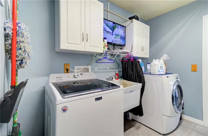 Laundry room featuring cabinet space, washing machine and clothes dryer, and light tile patterned floors