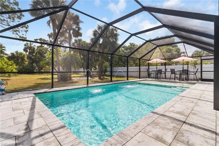 View of pool featuring a lanai, a fenced backyard, a sunroom, and patio surround
