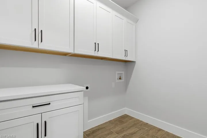 Washroom with cabinet space, light wood-style flooring, washer hookup, and hookup for an electric dryer