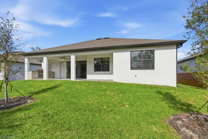 Back of property featuring ceiling fan, a patio area, roof with shingles, an outdoor kitchen, and stucco siding