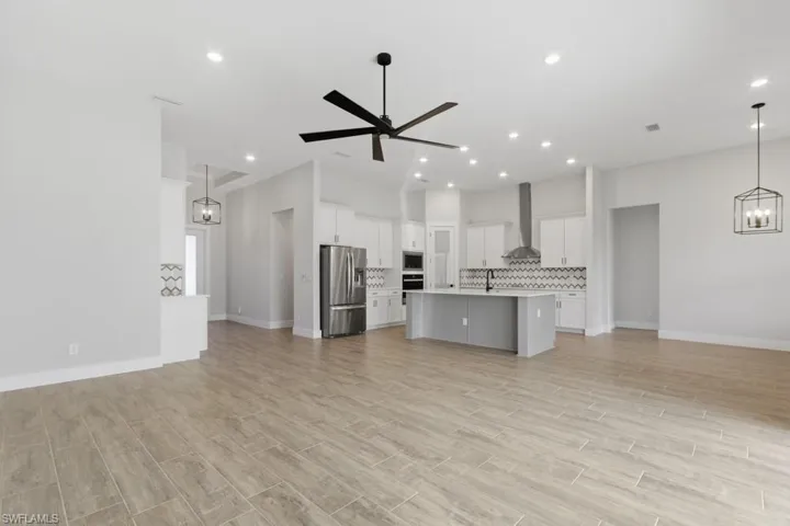 Unfurnished living room featuring a chandelier, a ceiling fan, luxury tile flooring, and recessed lighting