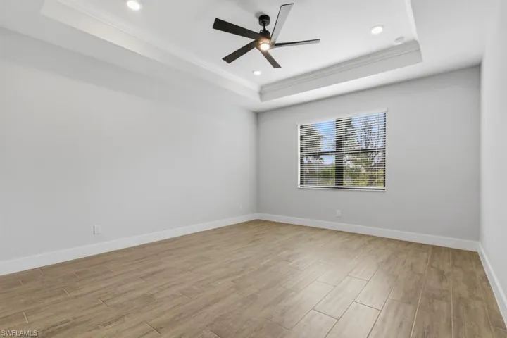 Master bedroom with tray ceiling, fan, and luxury tile flooring