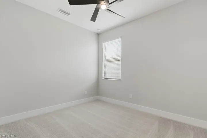 Unfurnished room with light colored carpet and a ceiling fan