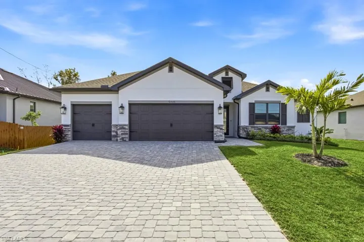 View of front of property featuring decorative driveway, stone siding, stucco siding, and an attached garage