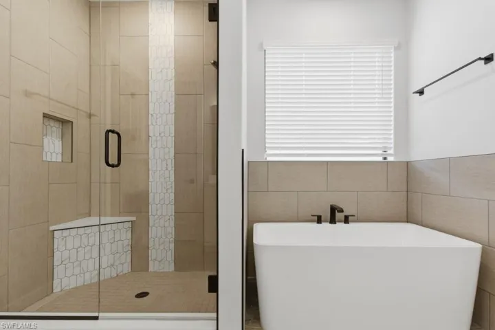 Full bathroom featuring a freestanding tub, a stall shower, and tile walls