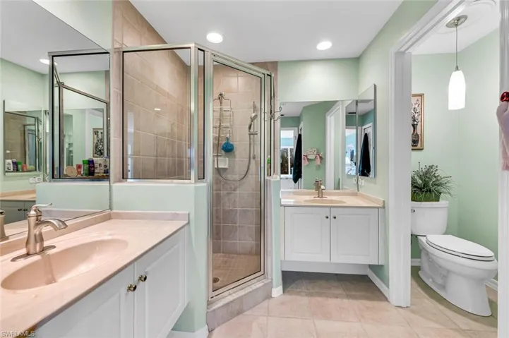 Bathroom with tile patterned flooring, toilet, vanity, and walk in shower
