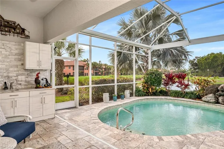 View of pool with a patio area and glass enclosure