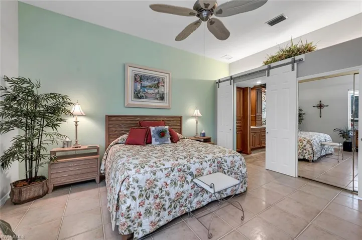 Bedroom featuring a barn door, ceiling fan, and light tile patterned flooring