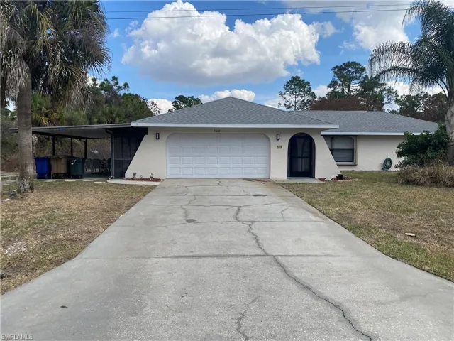 Ranch-style home with an attached garage, driveway, roof with shingles, a front yard, and stucco siding