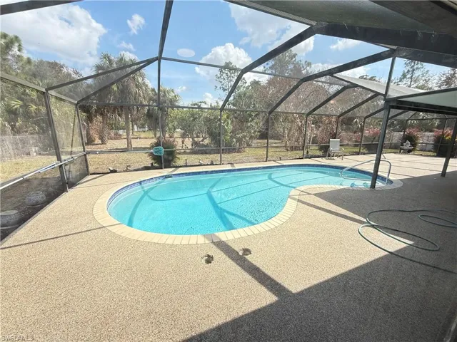 Swimming pool featuring a sunroom, glass enclosure, and a patio area