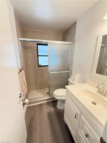 Full bath featuring vanity, laminate floors, and a stall shower
