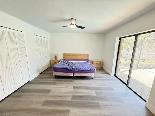 Bedroom with multiple closets, access to outside, laminate floors, and a ceiling fan