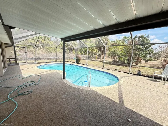 Swimming pool featuring a sunroom, a patio area, and glass enclosure
