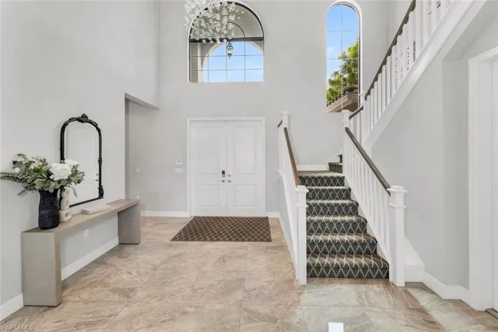 Tiled foyer featuring a towering ceiling and a chandelier