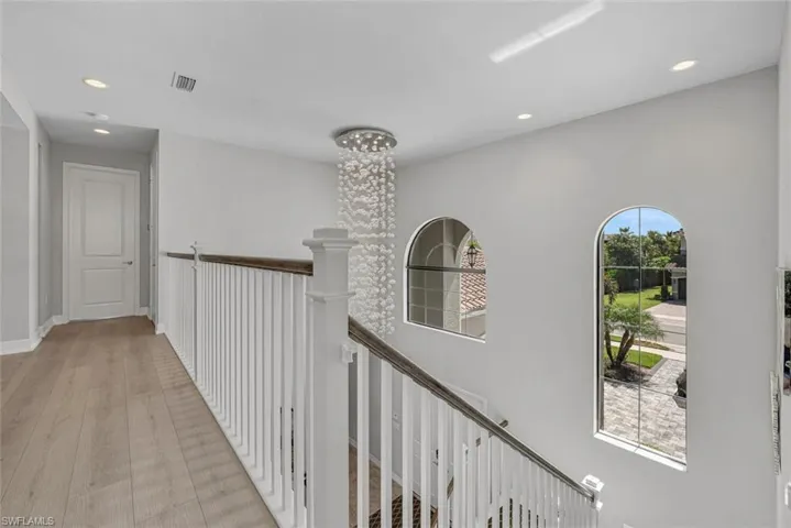 Hall with a notable chandelier and light wood flooring