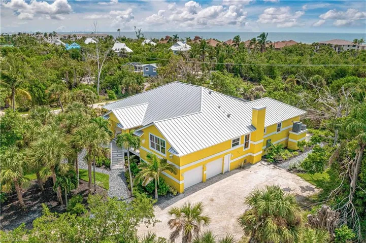 Two-story residence featuring a vibrant yellow exterior and a silver metal roof