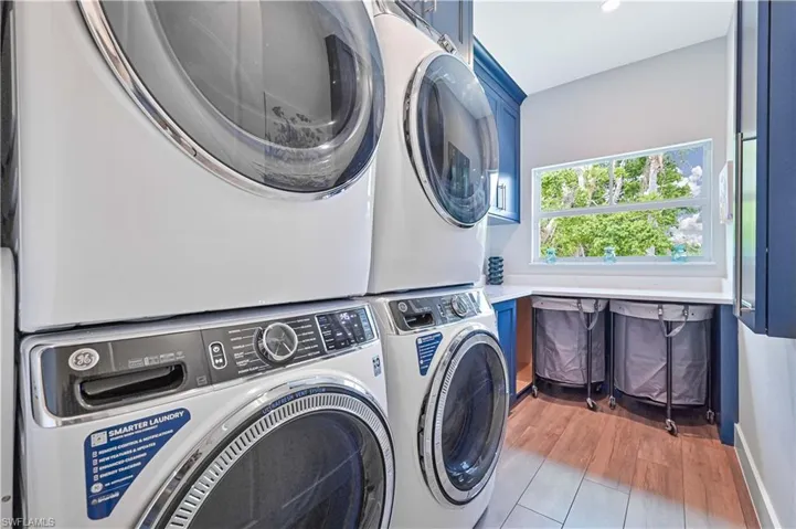 Dedicated laundry area featuring stacked front-load appliances and wood-finish flooring