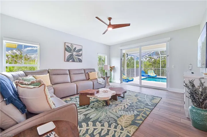 Spacious interior room featuring wood-finish flooring, a contemporary ceiling fan, and large windows