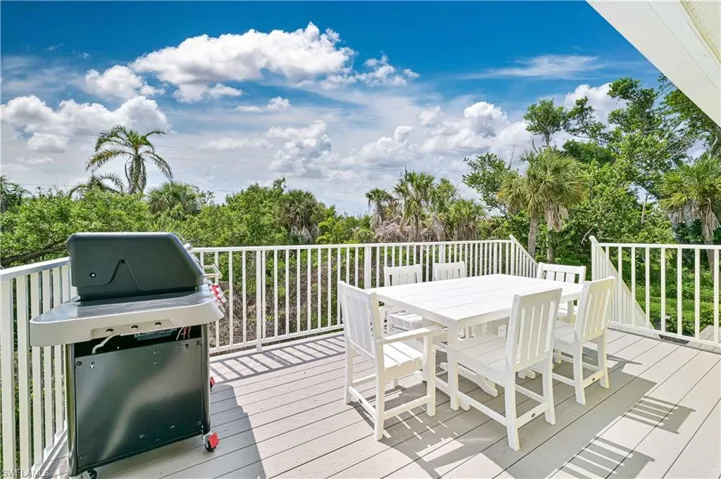 Spacious outdoor deck featuring composite decking, white railing, and extensive tropical landscaping
