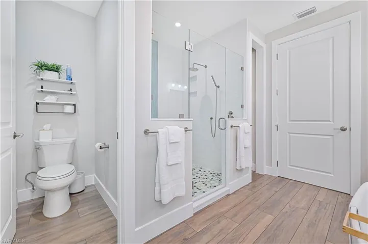 Modern bathroom featuring a frameless glass shower enclosure with a stone pebble floor, white subway tile surround, and dual shower heads